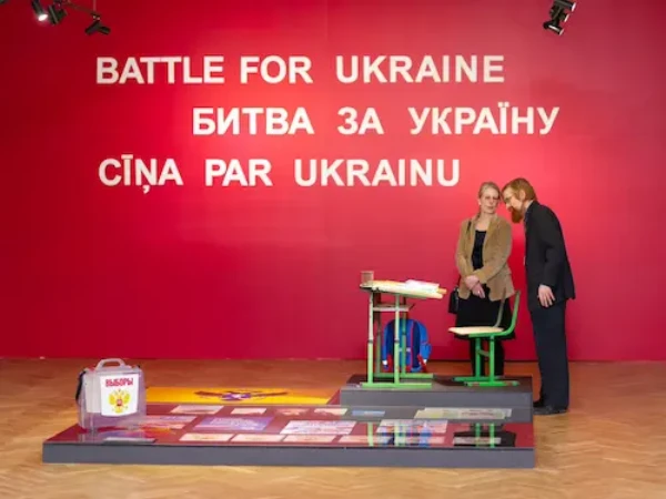 Нова пошта є партнером Музею і доставляє експозиції власним коштом. Цього разу в Ригу. Виставка «Битва за Україну»  має дві сюжетні лінії: показує потворне обличчя агресора та сміливі очі українських військових.
